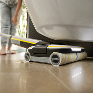 A person cleaning floors below furniture A person cleaning floors below furniture